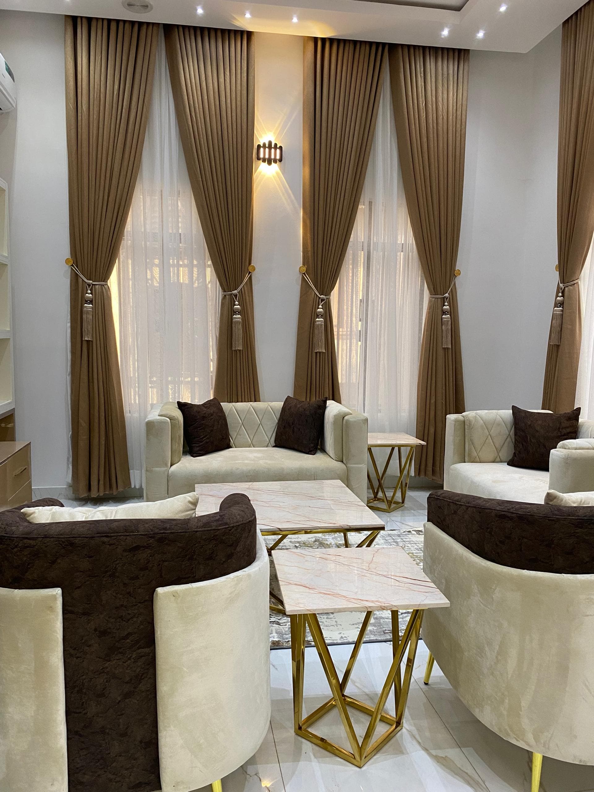 A luxurious living room with marble tables, layered lighting, and rich blue seating.